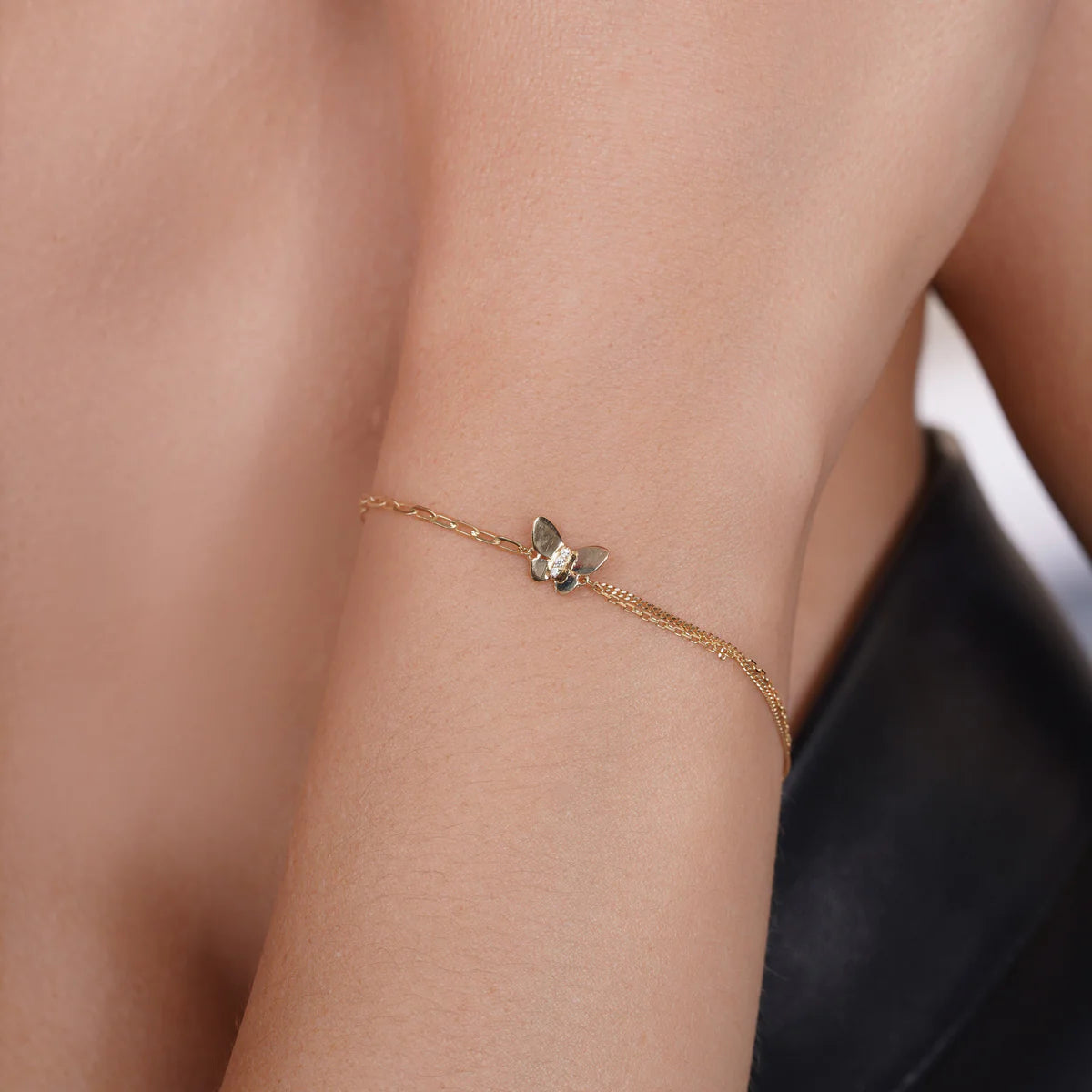 Close view of the 14 karat gold butterfly charm on the paperclip bracelet