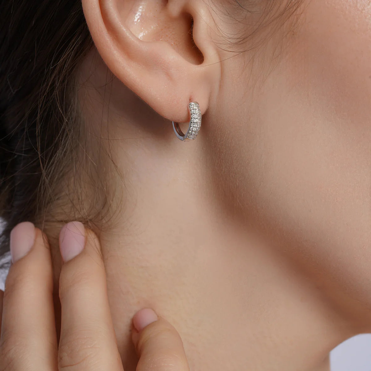 Sterling silver diamond huggie hoop earring shown worn on the ear